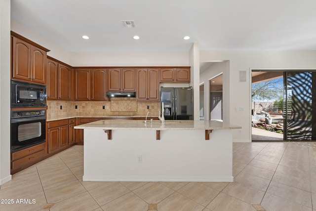 kitchen featuring visible vents, a breakfast bar area, black appliances, and backsplash