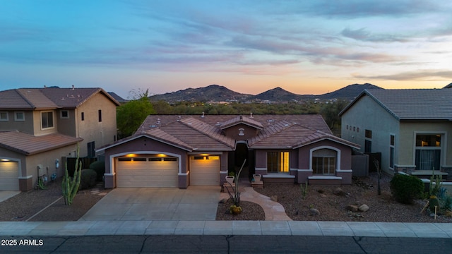 view of front of house featuring a tile roof, concrete driveway, stucco siding, an attached garage, and a mountain view