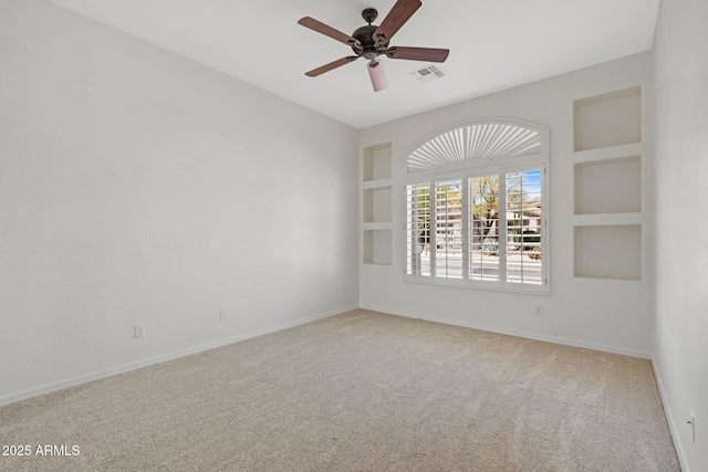 empty room featuring carpet floors, built in features, baseboards, and ceiling fan
