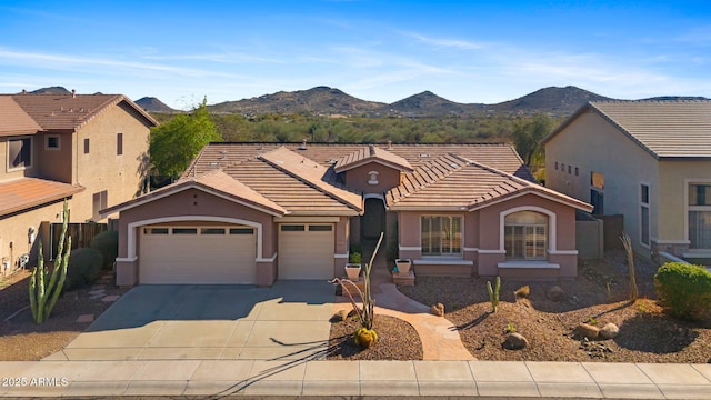 view of front of home featuring a tile roof, concrete driveway, stucco siding, an attached garage, and a mountain view