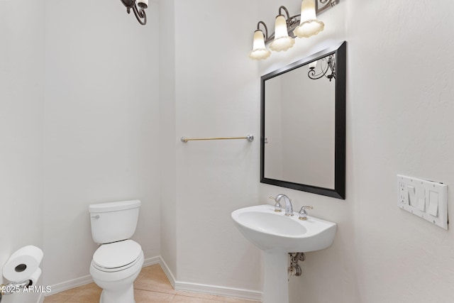 half bath featuring tile patterned flooring, a sink, toilet, and baseboards