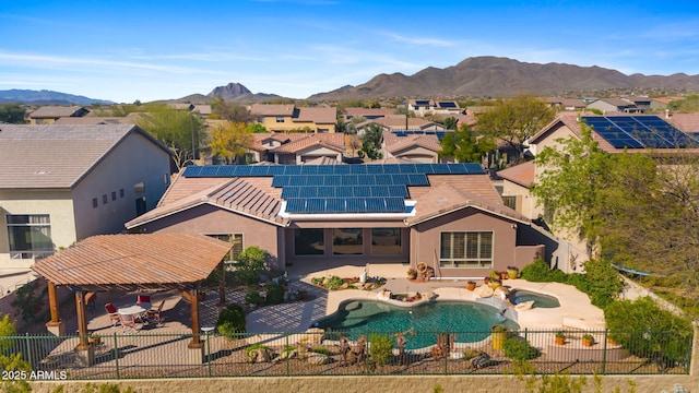 rear view of property with roof mounted solar panels, a fenced backyard, a tile roof, a mountain view, and a patio area