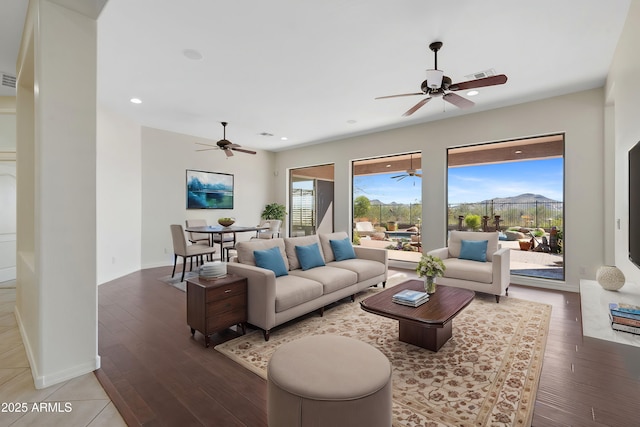 living area featuring baseboards, visible vents, a ceiling fan, and wood finished floors