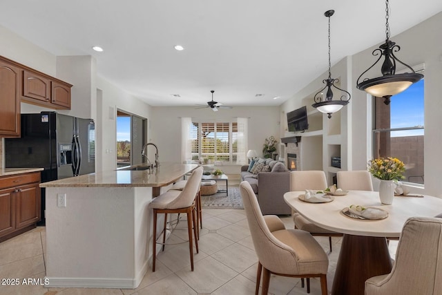 dining room featuring light tile patterned flooring, recessed lighting, a glass covered fireplace, and a ceiling fan