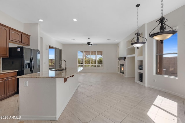 kitchen with open floor plan, black fridge with ice dispenser, built in shelves, a ceiling fan, and a glass covered fireplace