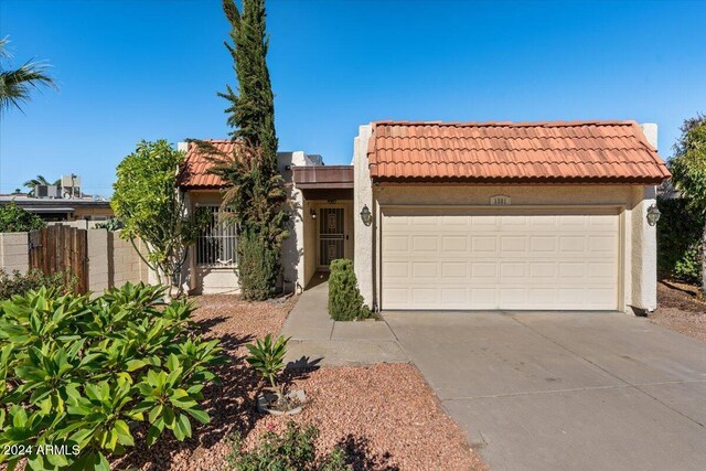 mediterranean / spanish-style home with a tiled roof, driveway, stucco siding, and a garage