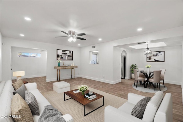 living room with ceiling fan with notable chandelier and light wood-type flooring