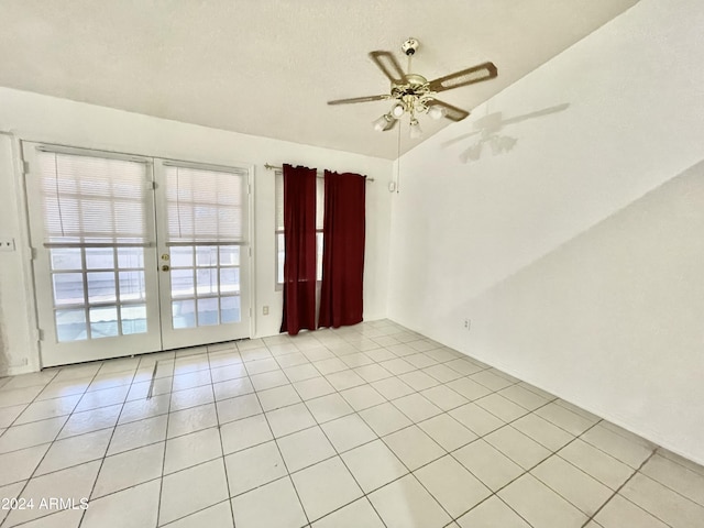 empty room with ceiling fan, french doors, light tile patterned flooring, and lofted ceiling