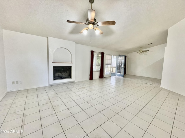 unfurnished living room with a textured ceiling, ceiling fan, light tile patterned floors, and vaulted ceiling