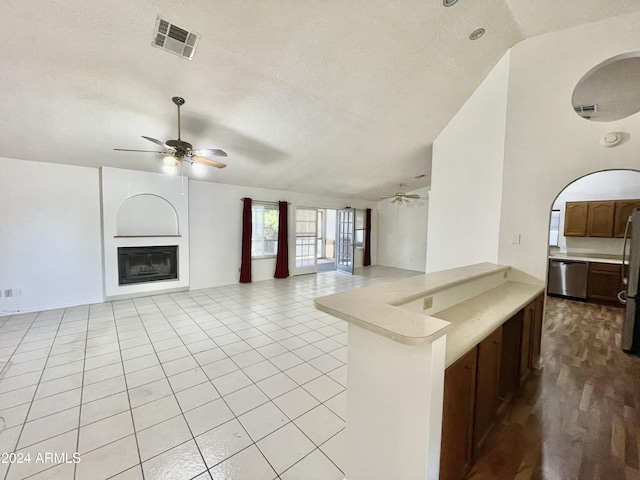 kitchen featuring lofted ceiling, ceiling fan, light tile patterned floors, and stainless steel appliances