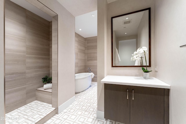 full bathroom with vanity, baseboards, visible vents, a freestanding tub, and a tile shower