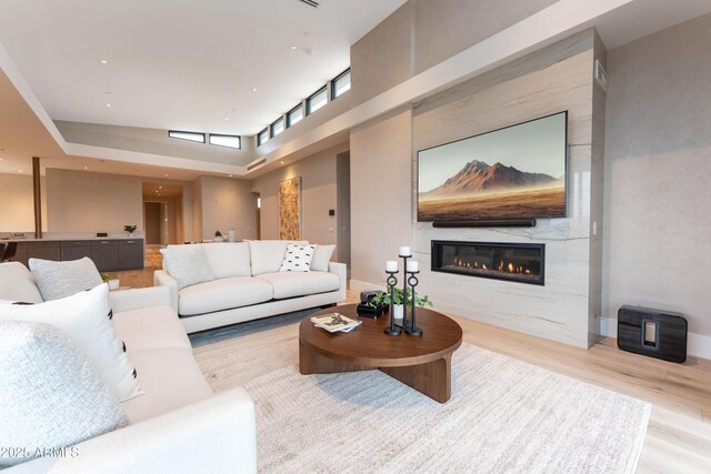 living area with wood finished floors, a fireplace, baseboards, and a towering ceiling