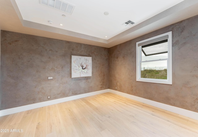 unfurnished room featuring visible vents, baseboards, and wood finished floors