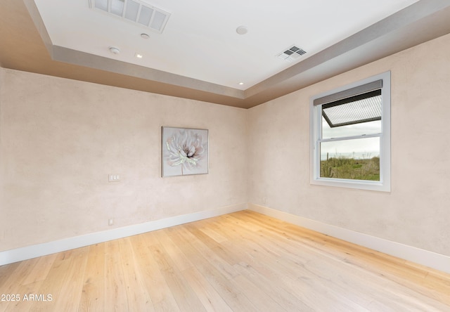 unfurnished room with baseboards, visible vents, and wood-type flooring