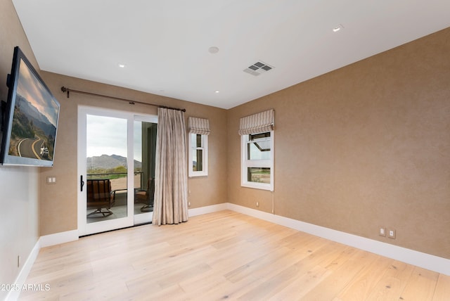 unfurnished room featuring visible vents, baseboards, and wood finished floors