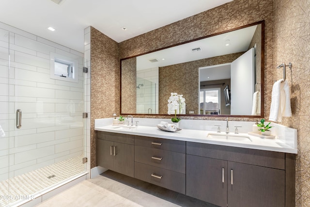 bathroom featuring double vanity, visible vents, a stall shower, and a sink