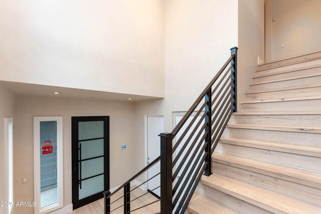 staircase featuring wood finished floors and a towering ceiling