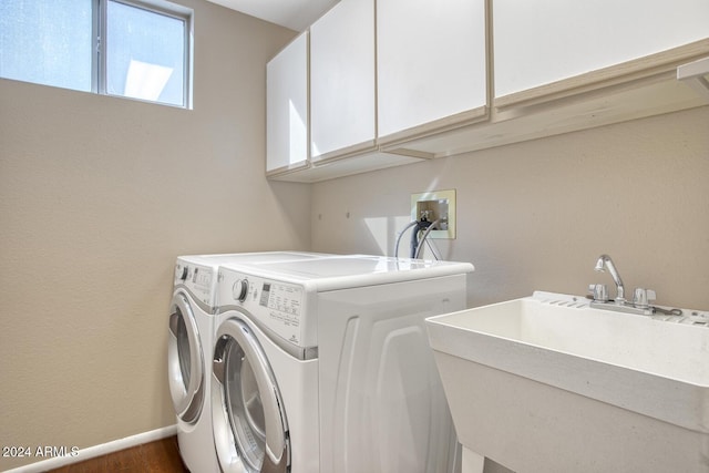 clothes washing area featuring washer and dryer, sink, and cabinets