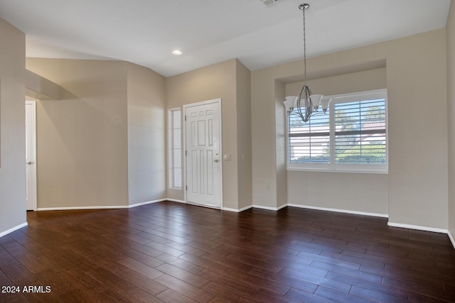 empty room featuring dark wood-type flooring and a chandelier