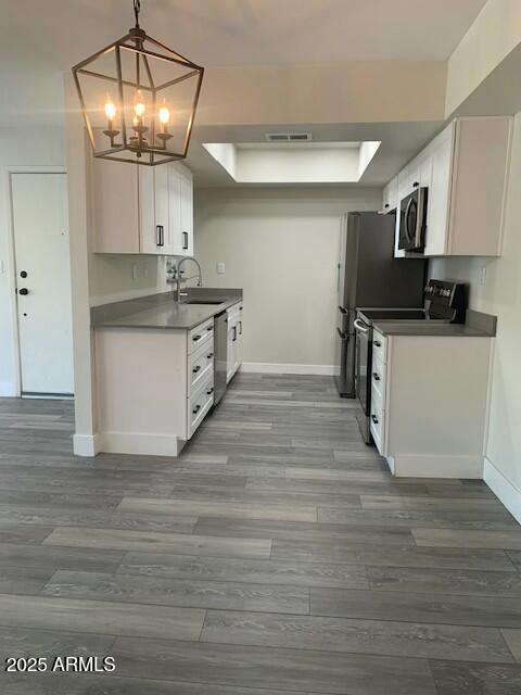 kitchen with white cabinetry, a chandelier, hanging light fixtures, sink, and stainless steel appliances