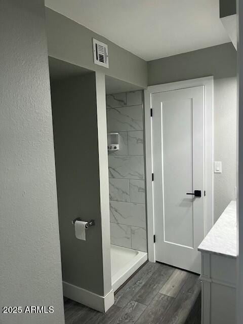 bathroom featuring vanity, hardwood / wood-style floors, and a tile shower