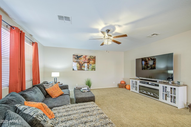 living area with carpet, visible vents, and ceiling fan