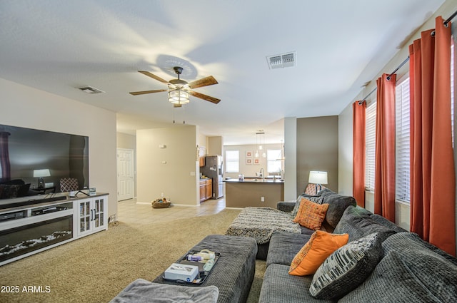 living room with light colored carpet, baseboards, a ceiling fan, and visible vents