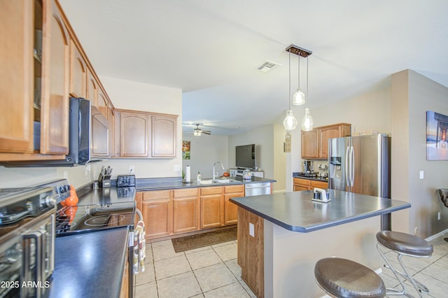 kitchen featuring stainless steel appliances, visible vents, a kitchen bar, light tile patterned floors, and dark countertops