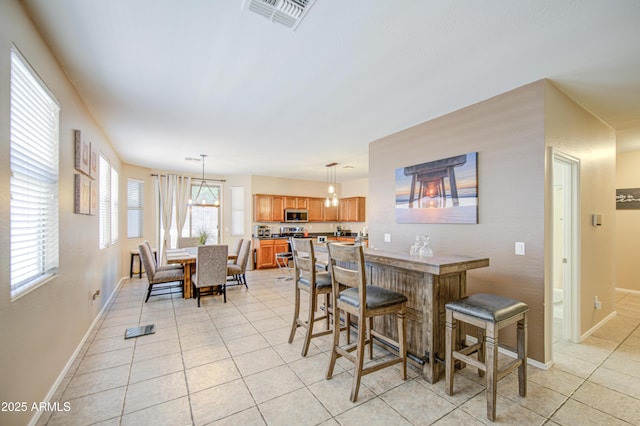 dining area featuring light tile patterned floors, visible vents, and baseboards