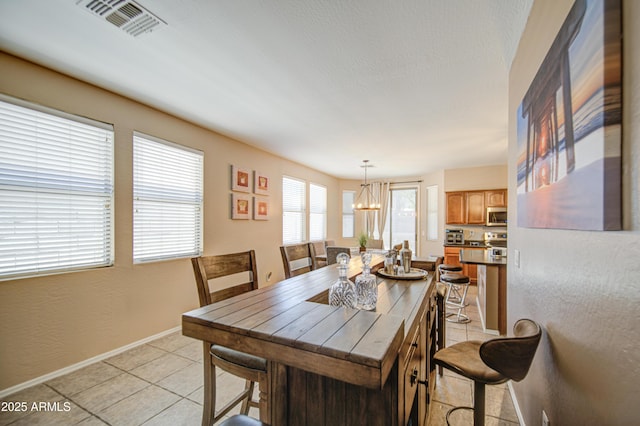 dining room featuring light tile patterned floors, a notable chandelier, visible vents, and baseboards