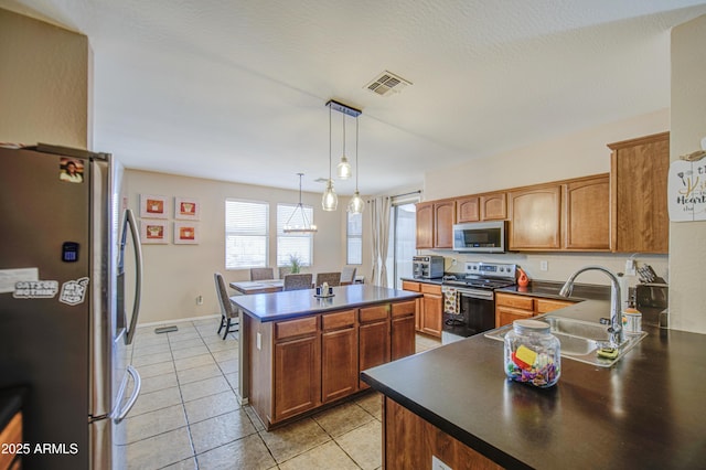 kitchen with dark countertops, visible vents, appliances with stainless steel finishes, and a sink