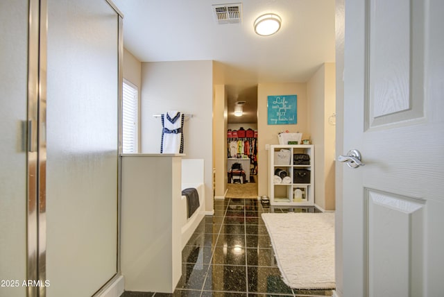 full bath with granite finish floor, a walk in closet, visible vents, baseboards, and a shower stall