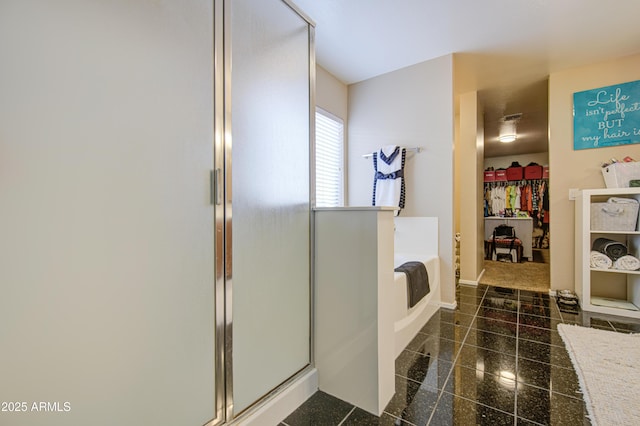 full bathroom with a stall shower, granite finish floor, a walk in closet, baseboards, and a bath