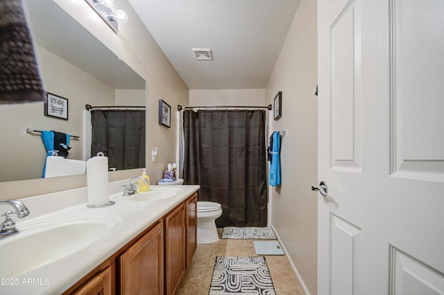 full bathroom featuring a sink, double vanity, toilet, and tile patterned floors