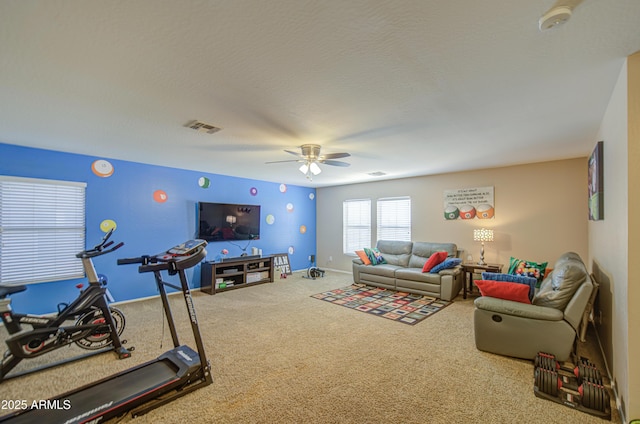 living area with a textured ceiling, visible vents, ceiling fan, carpet flooring, and baseboards