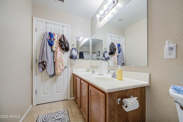 bathroom with double vanity, visible vents, tile patterned flooring, and a sink