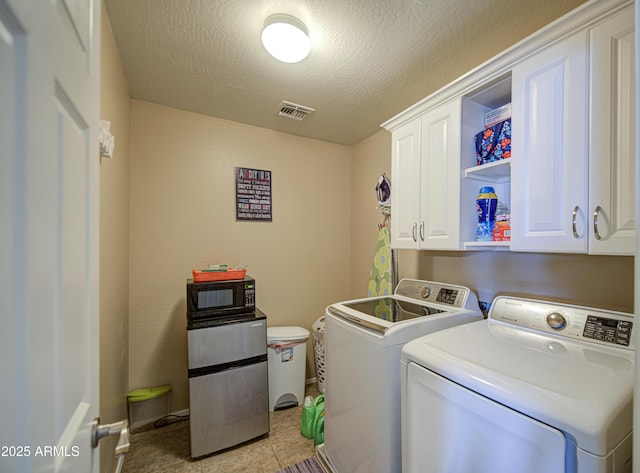 laundry area with washing machine and dryer, a textured ceiling, baseboards, visible vents, and cabinet space