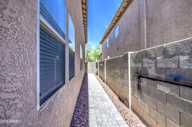 view of side of home featuring fence and stucco siding
