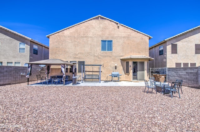 back of property featuring a fenced backyard, a gazebo, a patio area, and stucco siding