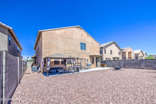 rear view of house with a gazebo, a patio area, central AC, stucco siding, and a fenced backyard