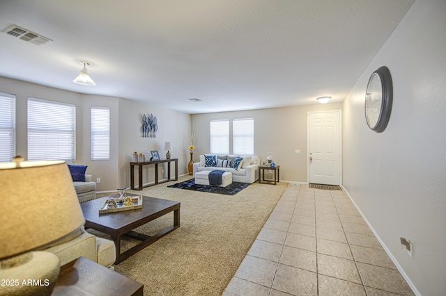 living area featuring baseboards, light colored carpet, visible vents, and light tile patterned flooring