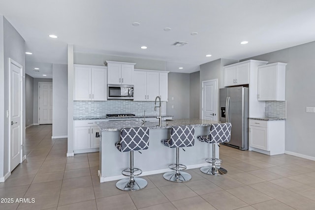 4628 W Greenleaf Dr, San Tan Valley, AZ 85144 - kitchen with appliances with stainless steel finishes, decorative backsplash, an island with sink, white cabinets, and light stone countertops