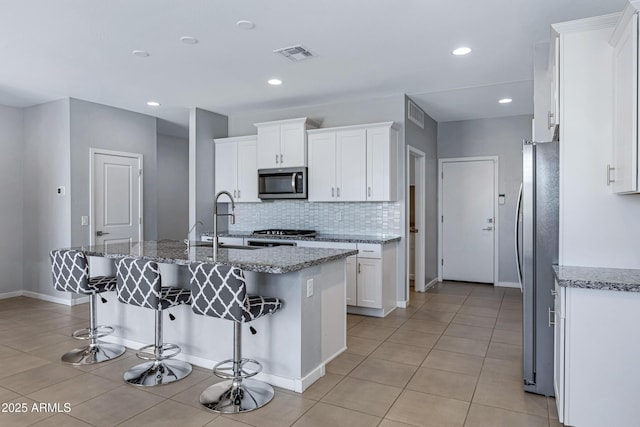 4628 W Greenleaf Dr, San Tan Valley, AZ 85144 - kitchen with appliances with stainless steel finishes, white cabinetry, a sink, backsplash, and a kitchen bar