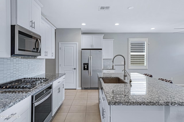 4628 W Greenleaf Dr, San Tan Valley, AZ 85144 - kitchen with stainless steel appliances, a center island with sink, a sink, decorative backsplash, and white cabinets