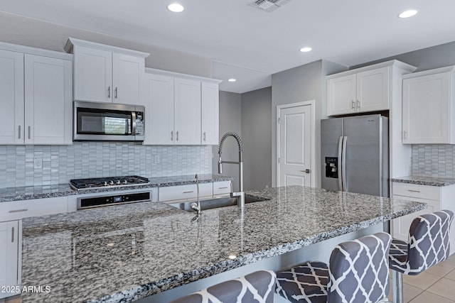4628 W Greenleaf Dr, San Tan Valley, AZ 85144 - kitchen with stainless steel appliances, a sink, white cabinetry, a breakfast bar area, and recessed lighting