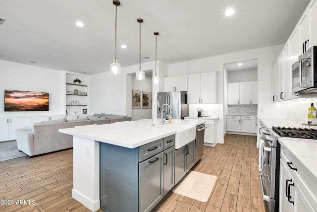 kitchen featuring stainless steel appliances, white cabinetry, and a kitchen island with sink