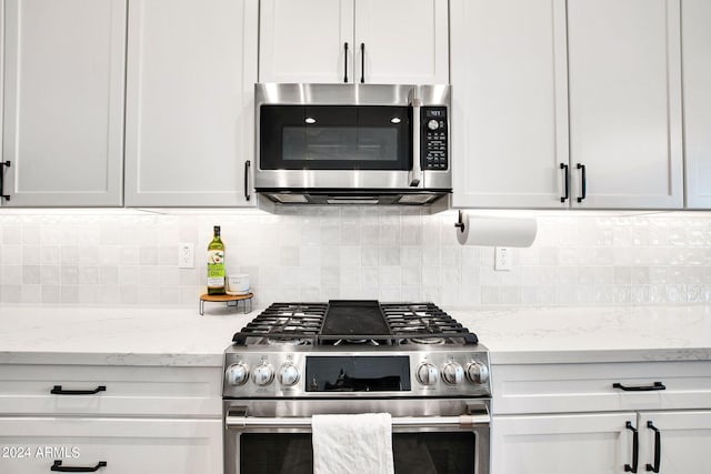 kitchen featuring light stone countertops, stainless steel appliances, white cabinetry, and tasteful backsplash