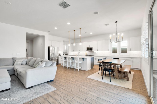 living room with a chandelier, light hardwood / wood-style floors, and sink