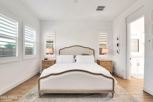 bedroom featuring light hardwood / wood-style floors and ensuite bath