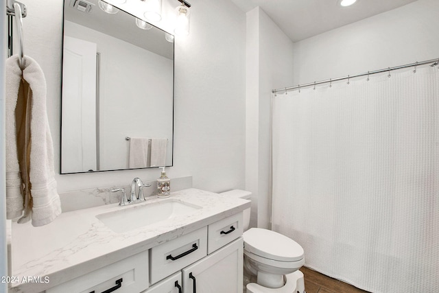 bathroom with vanity, toilet, and hardwood / wood-style flooring